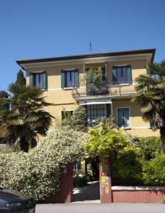 a large yellow building with a balcony and trees at Antica Villa Graziella in Marghera