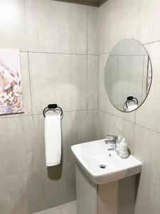 a white bathroom with a sink and a mirror at The Onyx Umhlanga in Durban