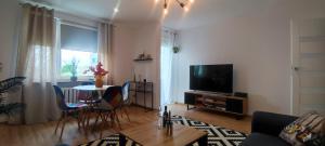 a living room with a television and a table with chairs at Apartament Lubin in Lubin