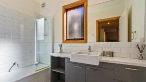 a bathroom with a sink and a mirror and a tub at Secret Hut in Dinner Plain +7 photos