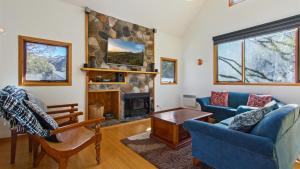 a living room with a stone fireplace and blue chairs at Secret Hut in Dinner Plain