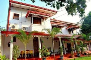 una grande casa bianca con alberi di fronte di Punchi Walawwa - Guest House - Holiday Bungalow a Anuradhapura