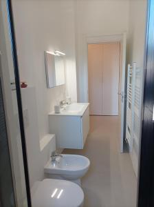 a white bathroom with a toilet and a sink at Lago d'Orta attico Sofia in Omegna +10 photos