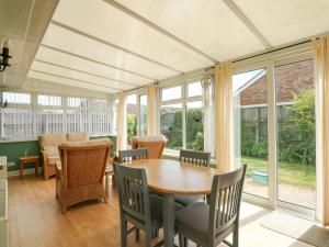 a dining room with a table and chairs and windows at Potter's Retreat in Dersingham