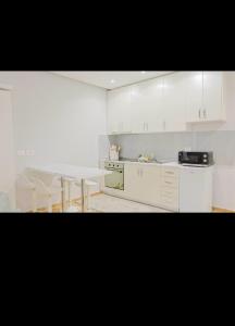 a kitchen with white cabinets and a white table at Ambient Apartaments in Durrës +6 photos