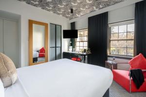 a bedroom with a white bed and a red chair at Peppers Gallery Hotel in Canberra