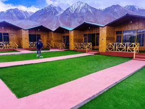 Ein Mann steht vor einem Gebäude mit Bergen im Hintergrund. in der Unterkunft Pangong Pearl in Man