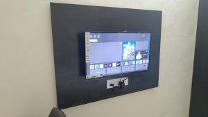 a flat screen tv on a black tiled wall at Paradise Homestay - Lodging and Boarding in Pune