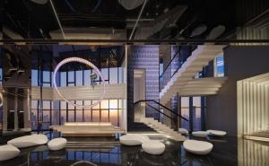 a lobby with a spiral staircase and white chairs at ISEYA Panoramic Hotel Chongqing Jiefangbei Raffles Plaza in Chongqing