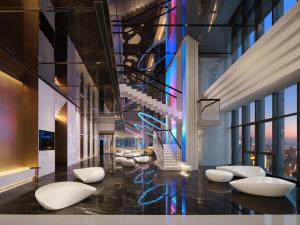 a lobby with white chairs and a staircase at ISEYA Panoramic Hotel Chongqing Jiefangbei Raffles Plaza in Chongqing