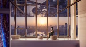 a woman sitting in front of a window in a building at ISEYA Panoramic Hotel Chongqing Jiefangbei Raffles Plaza in Chongqing