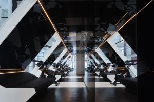 a gym with rows of exercise equipment and escalators at ISEYA Panoramic Hotel Chongqing Jiefangbei Raffles Plaza in Chongqing