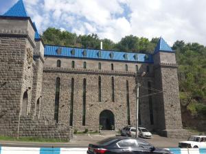 a large brick building with a gate and cars parked at Venezia Palazzo Hotel in Yerevan