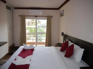 um quarto com uma grande cama branca com travesseiros vermelhos em Hotel Nevis em Pokhara