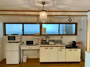 a kitchen with white cabinets and a chandelier at あまみ日和 奄美大島の宿 -Amami Biyori- in Amami