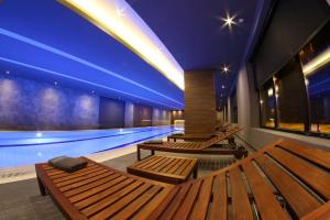 a swimming pool with wooden benches and a swimming pool at Apartmani Didić Kalman Zlatibor in Zlatibor