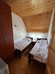 two beds in a room with wooden ceilings at Kuća Čepić in Žabljak