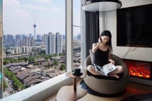 成都市にあるISEYA Serviced Apart-ment Chengdu Taikoo Li Flagshipの窓の前の椅子に座る女性