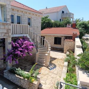 a house with a staircase and flowers in a yard at Apartments Villa Vanja in Povlja