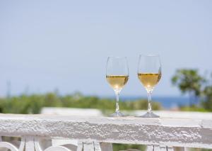 two glasses of white wine sitting on a railing at Kanelis Studios & Suites in Mytakas
