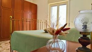 a bedroom with a bed and a vase with flowers in it at Al Pianotto, appartamento vintage ad Avola, vista Mare in Avola +17 photos