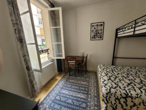 a bedroom with a bed and a table and a window at Cozy and nice homestay room - chambre d'hôte in Paris