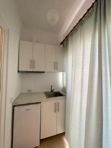 a kitchen with white cabinets and a sink next to a window at Keivi Guesthouse in Sarandë +17 photos