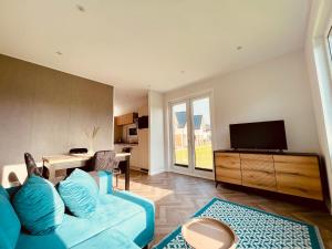 a living room with a blue couch and a television at New Corner Holiday Camp in Niechorze