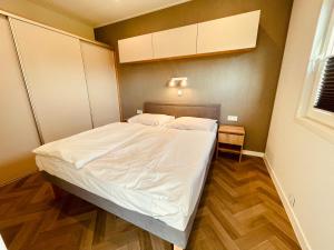 a small bedroom with a bed with white sheets at New Corner Holiday Camp in Niechorze +8 photos