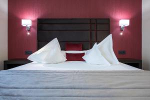 ein Schlafzimmer mit einem großen weißen Bett und roten Kissen in der Unterkunft Old Town Hotel in Timişoara