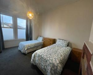 una camera da letto con due letti, un comò e una finestra di Low Cost Accommodation a Dunedin