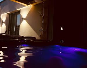 a dark room with a tub with blue lights at Pura Vida Spa - gîte avec spa extérieur couvert in Écaillon