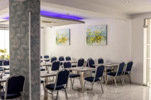 une salle à manger avec des tables, des chaises et des peintures dans l'établissement Milea Hotel, à Ayia Napa