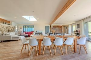 a kitchen and living room with a wooden table and white chairs at Villa Léonie - piscine intérieure in Kerlouan