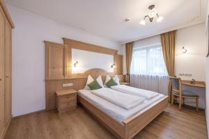 a bedroom with a bed with a desk and a chair at Residence Diana Apartment 101 in Terento