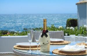 a bottle of wine sitting on a table with glasses at Tranquil Oceanfront Escape, One-Bedroom Haven in Mijas