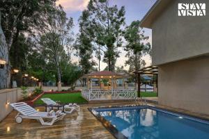 a swimming pool with two lounge chairs next to a house at Elegant Escapes with Swimming Pool, Lawn & Bonfire at Panchgani by StayVista in Panchgani