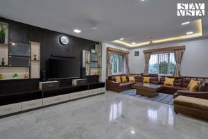 a living room with a couch and a tv at Elegant Escapes with Swimming Pool, Lawn & Bonfire at Panchgani by StayVista in Panchgani