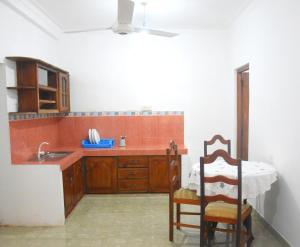 una cucina con armadi in legno, lavandino e sedia di Insa Guest House Kandy a Kandy