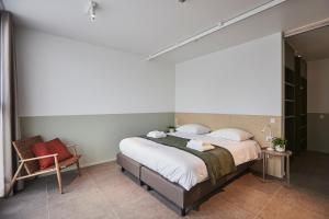 a bedroom with a large bed and a chair at Het Kasterhuis - Groepsverblijf in Wetteren