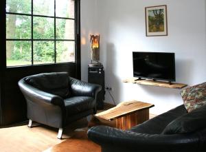 a living room with a couch and a chair and a television at Ferienwohnung im Fehnland 25197 in Bunde
