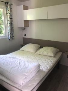 duże łóżko z białą pościelą i oknem w obiekcie mobil-home 4/6 pers w mieście Pont-Aven