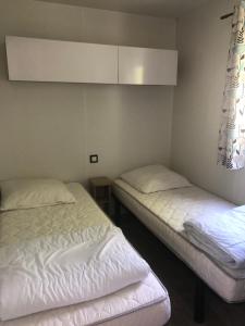 dwa łóżka w pokoju z białymi prześcieradłami w obiekcie mobil-home 4/6 pers w mieście Pont-Aven +11 zdjęć
