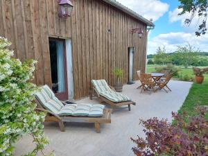 a patio with chairs and a table and a building at Gîte Cosy Grand confort dans un écrin de verdure in Agudelle