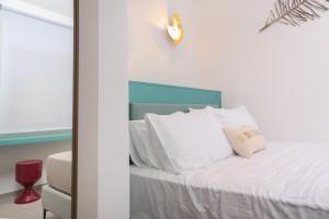 ein Bett mit weißen Kissen und einer Uhr an der Wand in der Unterkunft Blue Sand Apartment in Pefkohori + 18 Fotos