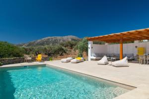 a swimming pool with pillows on a patio next to a house at Captain's Home ART in Artemonas