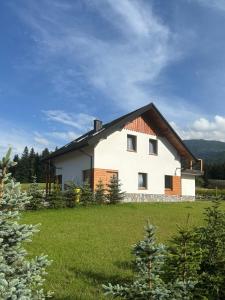 a white house with a black roof on a green field at Domek SAMI SWOI in Zawoja
