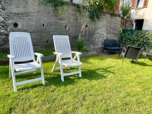 two white chairs sitting in the grass in a yard at I Tre Fratelli in Vignone