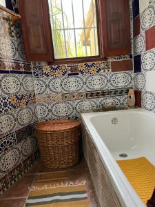 a bathroom with a tub and a window and a basket at Casa Aziza , le charme andalou in Lanjarón +30 photos