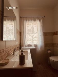 a bathroom with a sink and a toilet and a window at Sa domo de ziu Pedru in Sennori +21 photos
